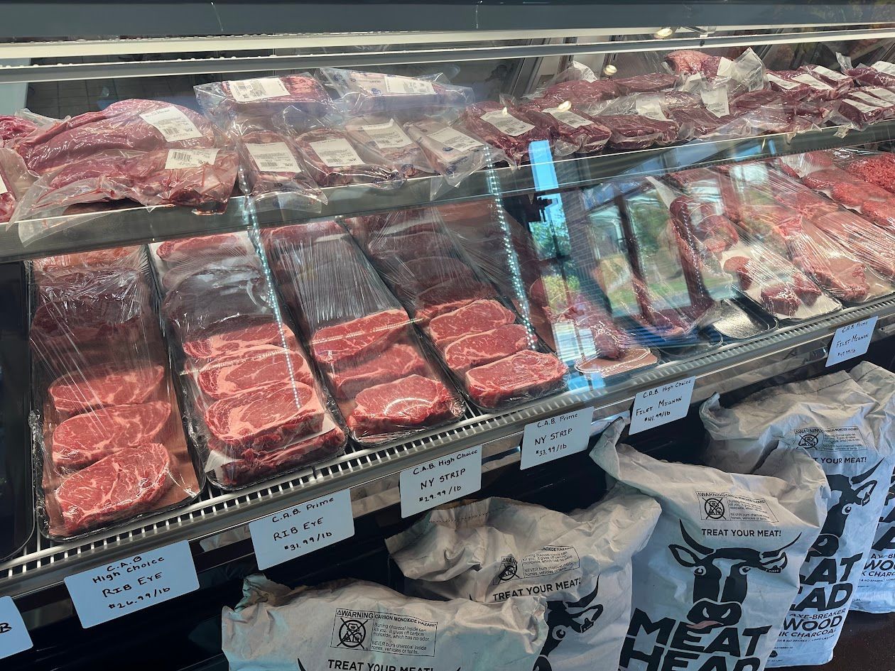 Meat display case with various cuts of red meat. White bags with