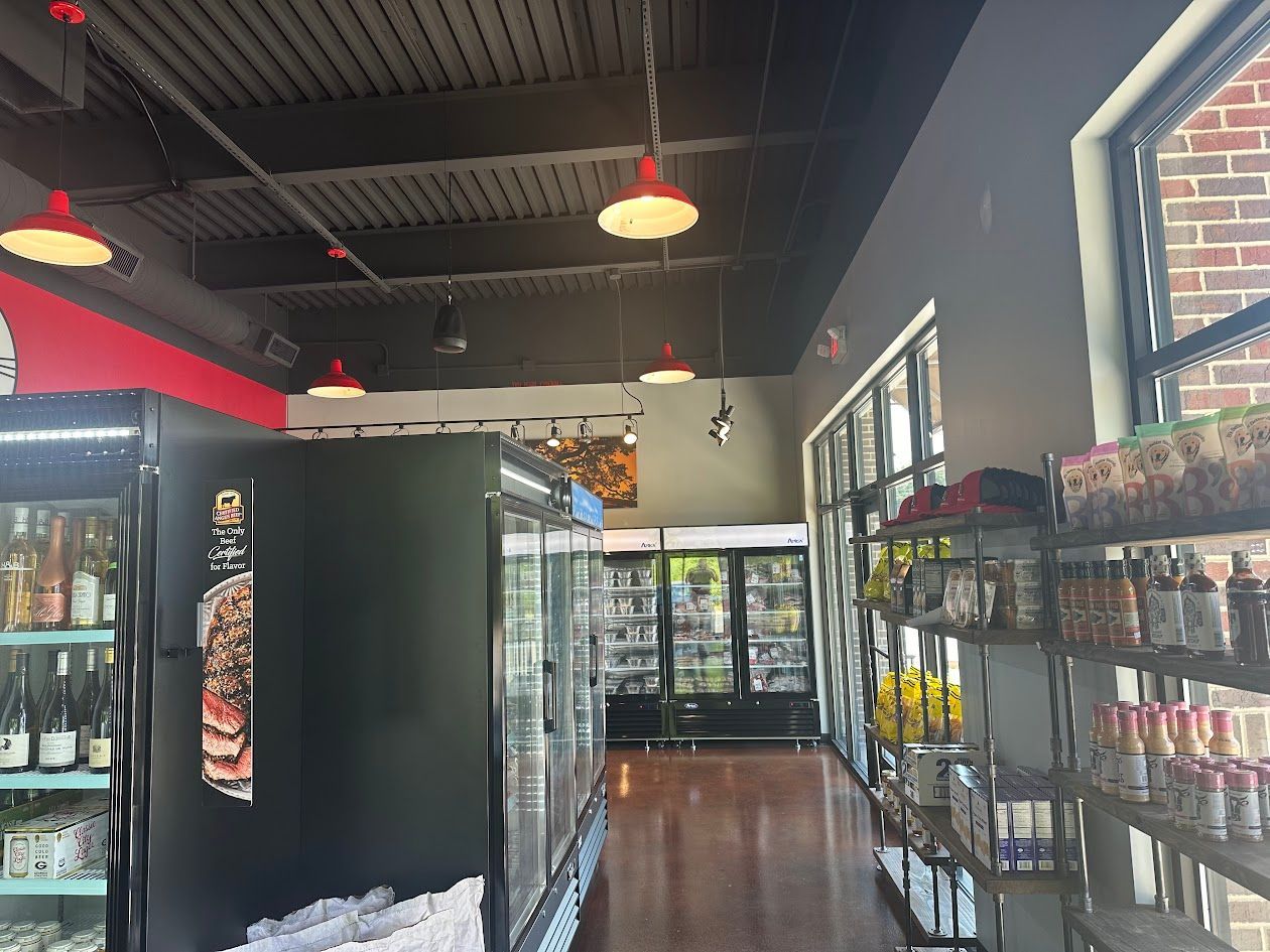 Interior shot of a store with refrigerated displays, red accent lights, and products on shelves.