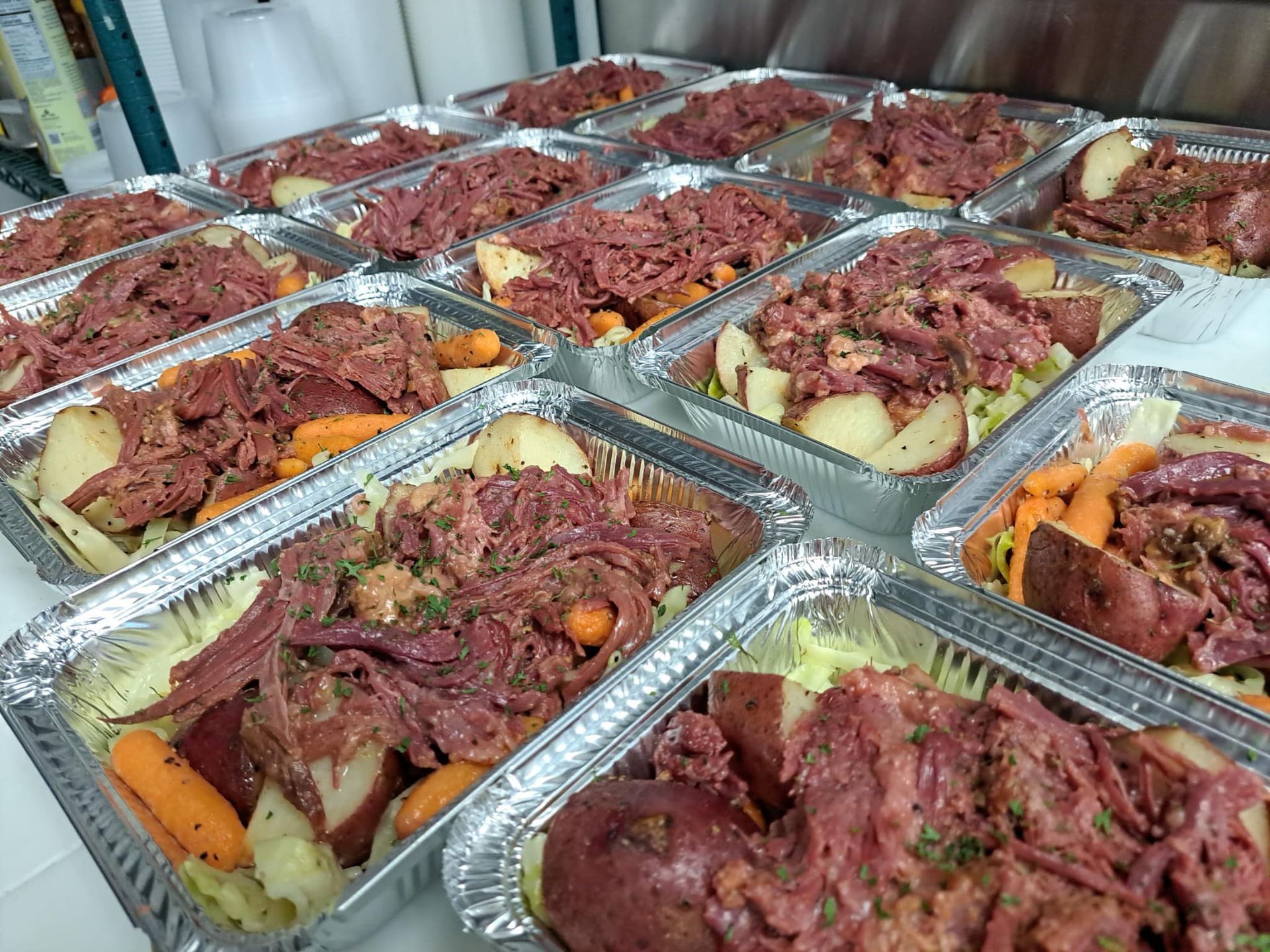 Prepared corned beef and vegetables in foil containers, ready to serve.