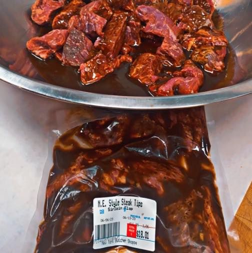 Marinated steak in a metal bowl and a sealed bag, ready to cook.
