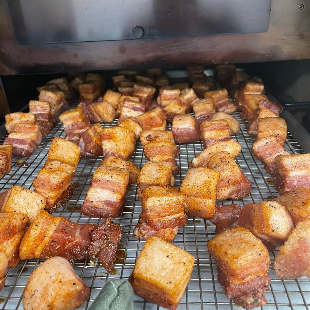 Cubed pork belly cooking on a rack inside an oven.