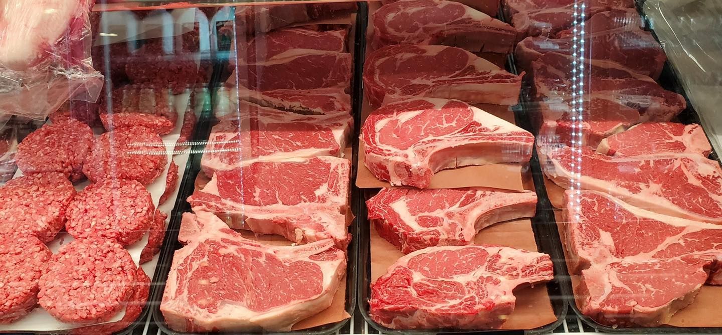 Various cuts of raw red meat displayed in a butcher shop case.