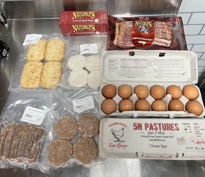 Assortment of packaged breakfast foods including eggs, bacon, sausage, hash browns, and biscuits.