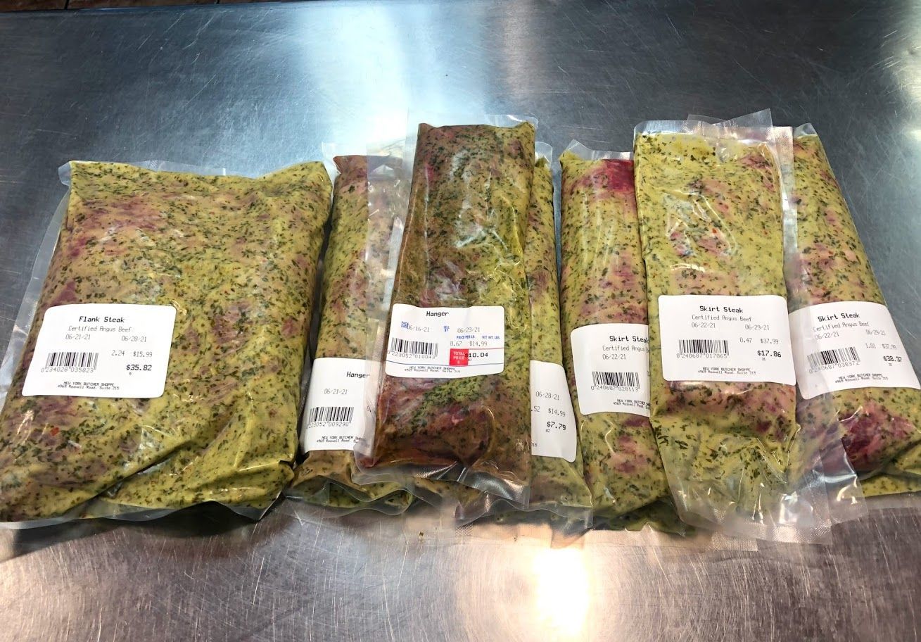 Vacuum-sealed packages of meat, likely marinated, with labels. Arranged on a metallic surface.