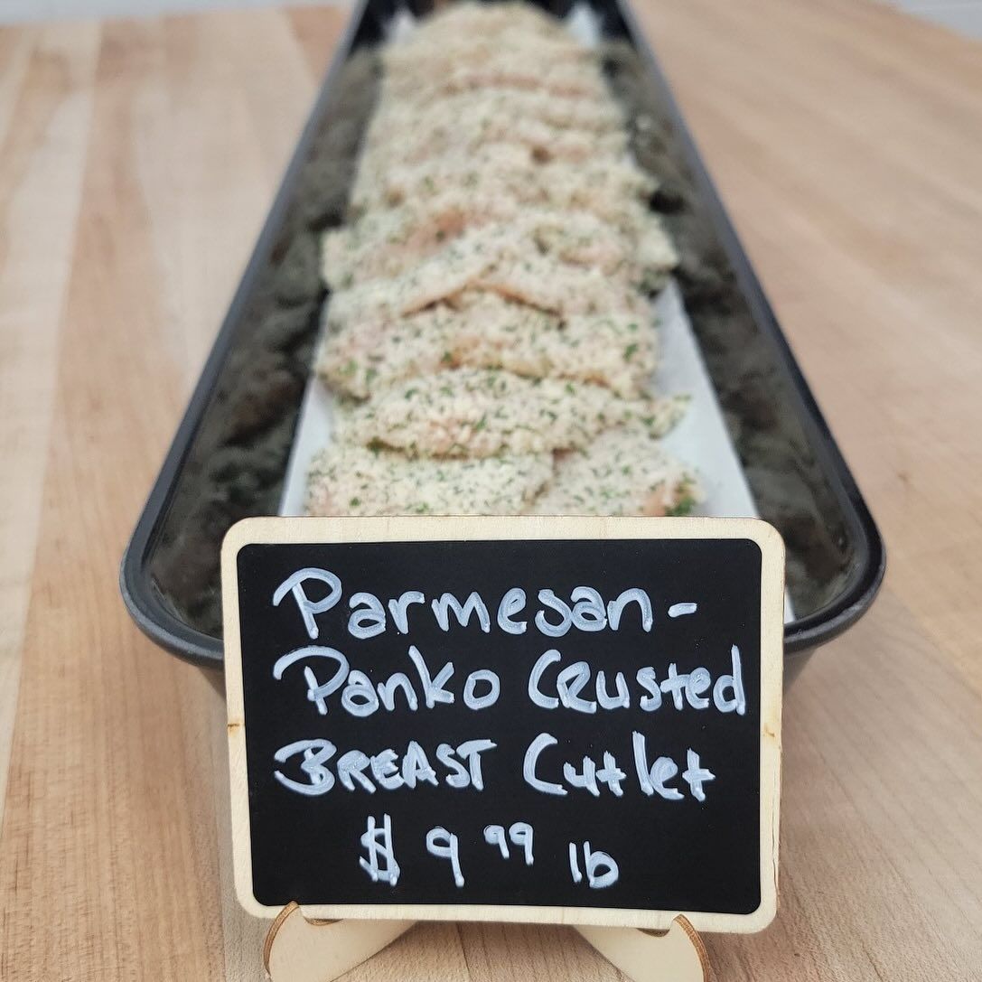 Parmesan-Panko crusted chicken cutlets in a black tray, with a sign: $9.99/lb.
