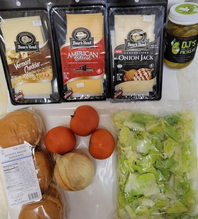 Groceries: cheese, pickles, tomatoes, onion, lettuce, and buns.