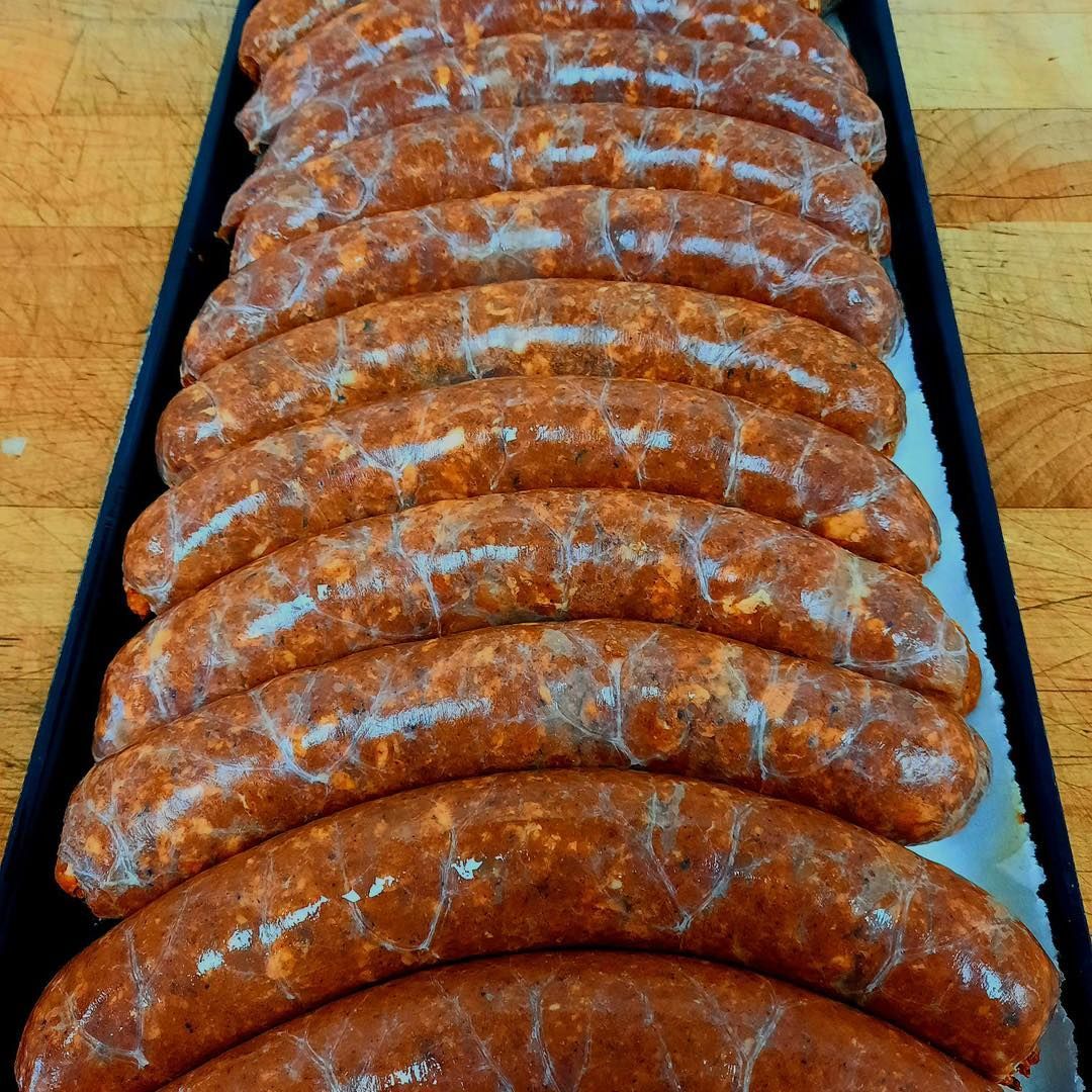 Rows of reddish-brown sausages in a rectangular tray.