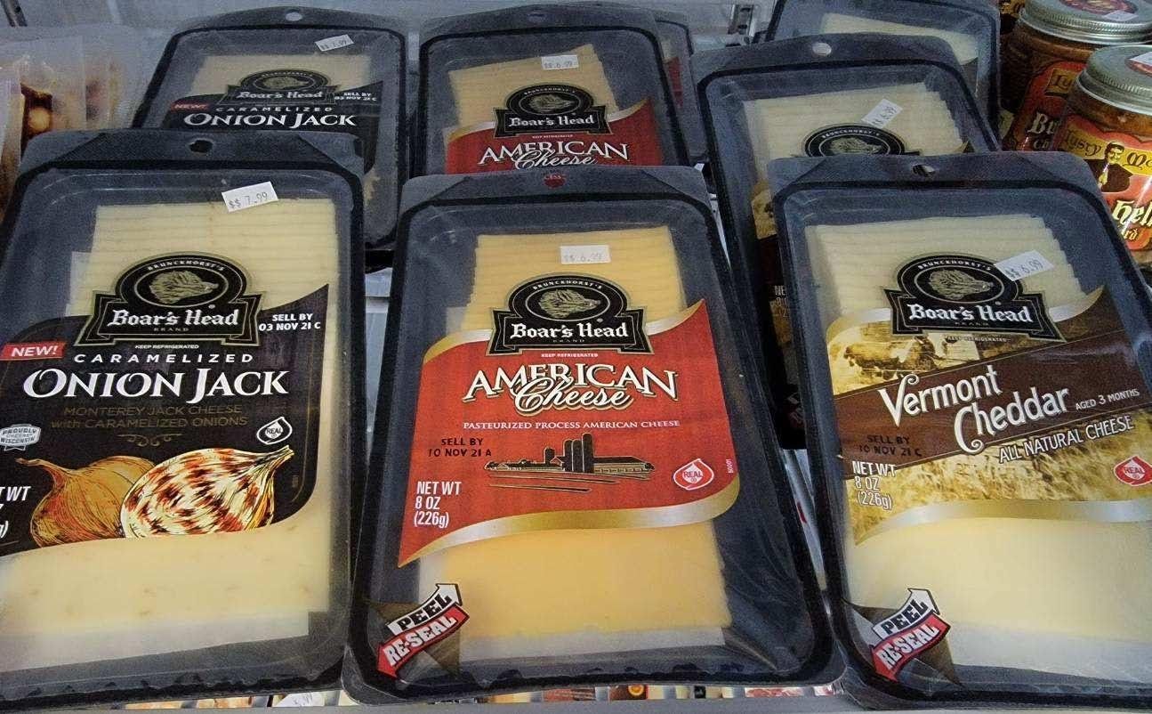 Packages of cheese in a store display. Varieties include Onion Jack, American, and Vermont Cheddar.