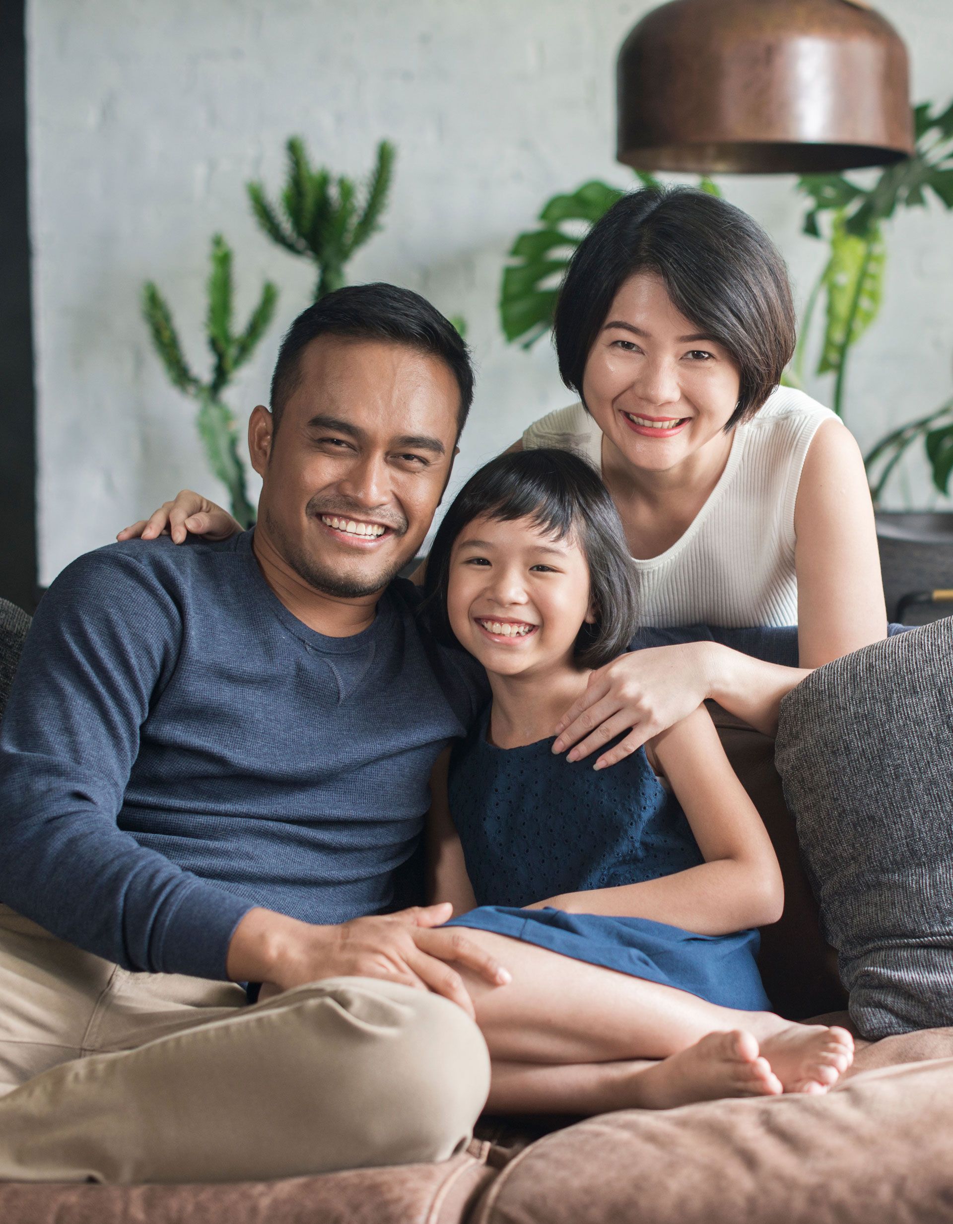 A family is posing for a picture while sitting on a couch.