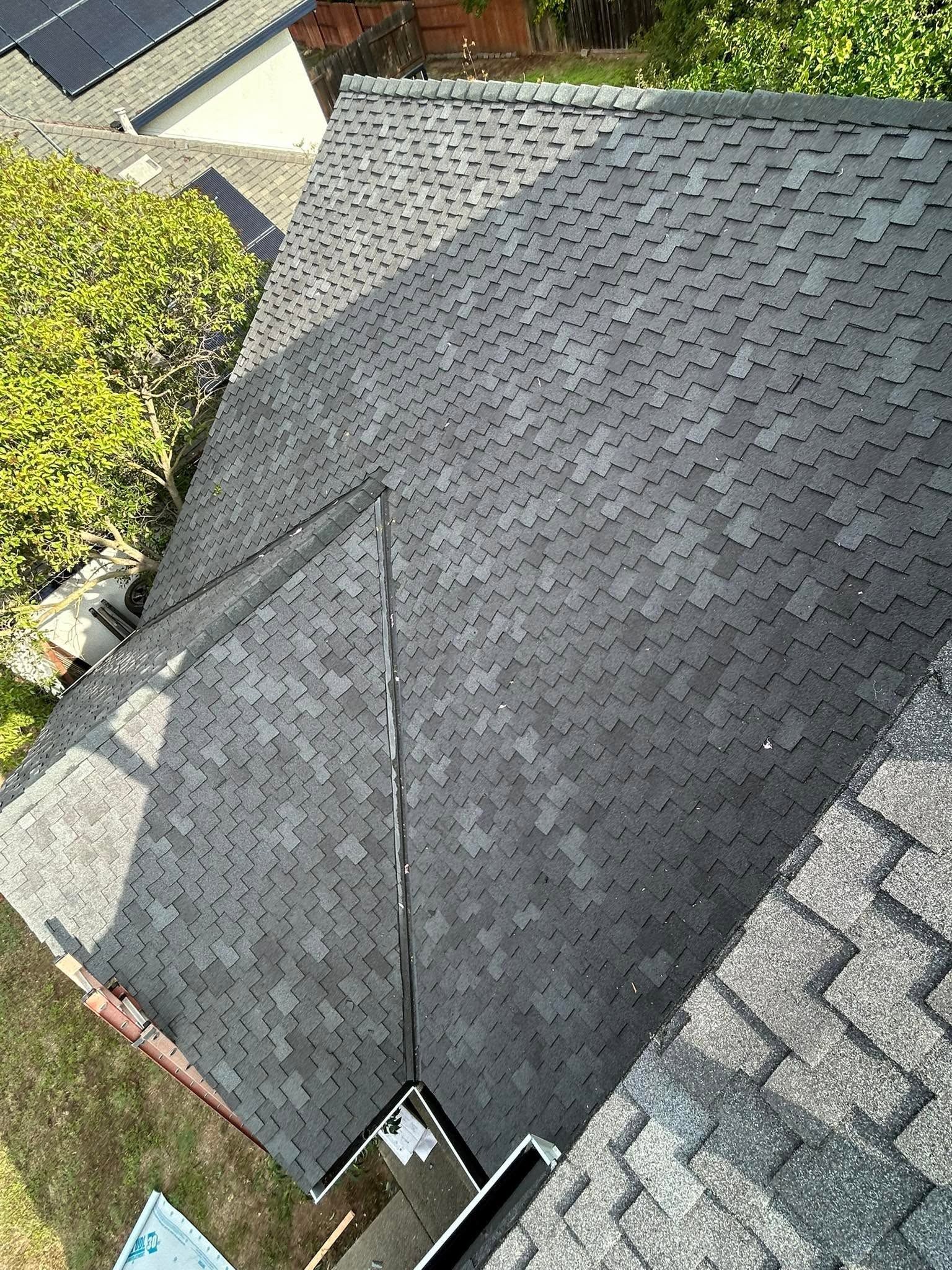 Steep gray shingled roof with a valley and a visible brown gutter at the bottom edge