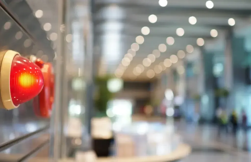 A red fire alarm is hanging on a wall in a building.