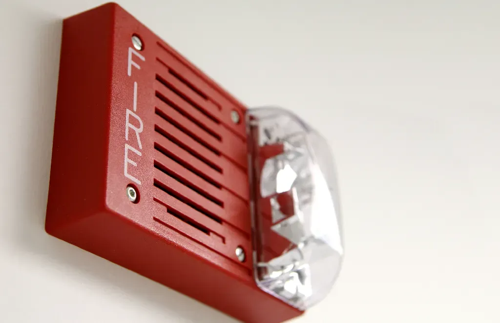 A red fire alarm is mounted on a white wall