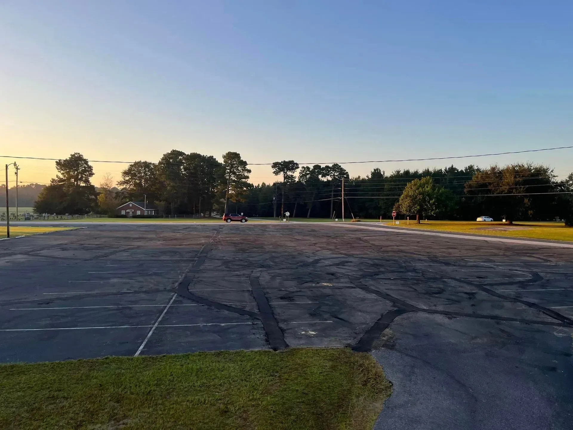Empty cracked parking lot at sunset with trees and a blue sky
