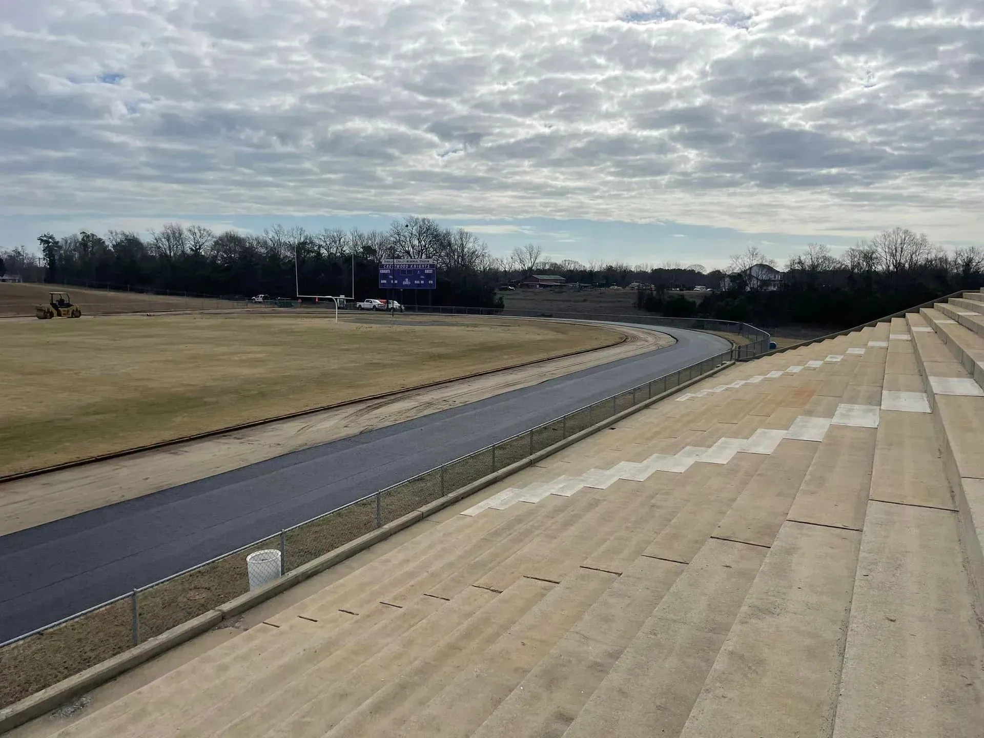 Empty racetrack under cloudy sky, with paved lanes and grassy infield.