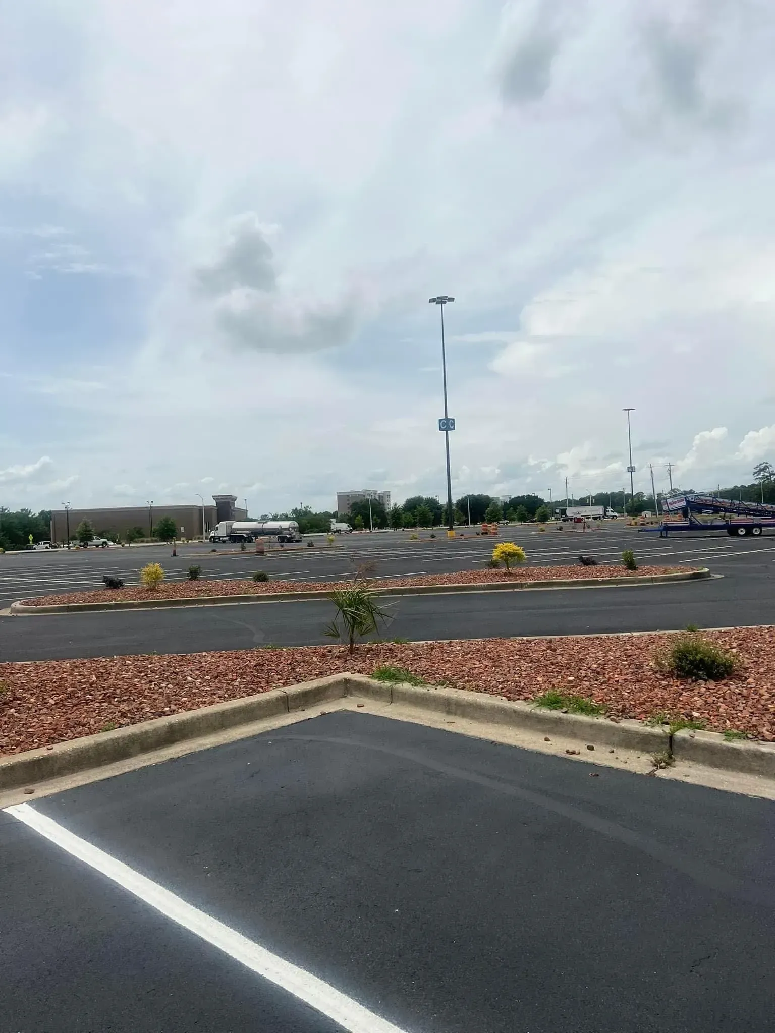 Empty parking lot beside a landscaped roundabout under a cloudy sky