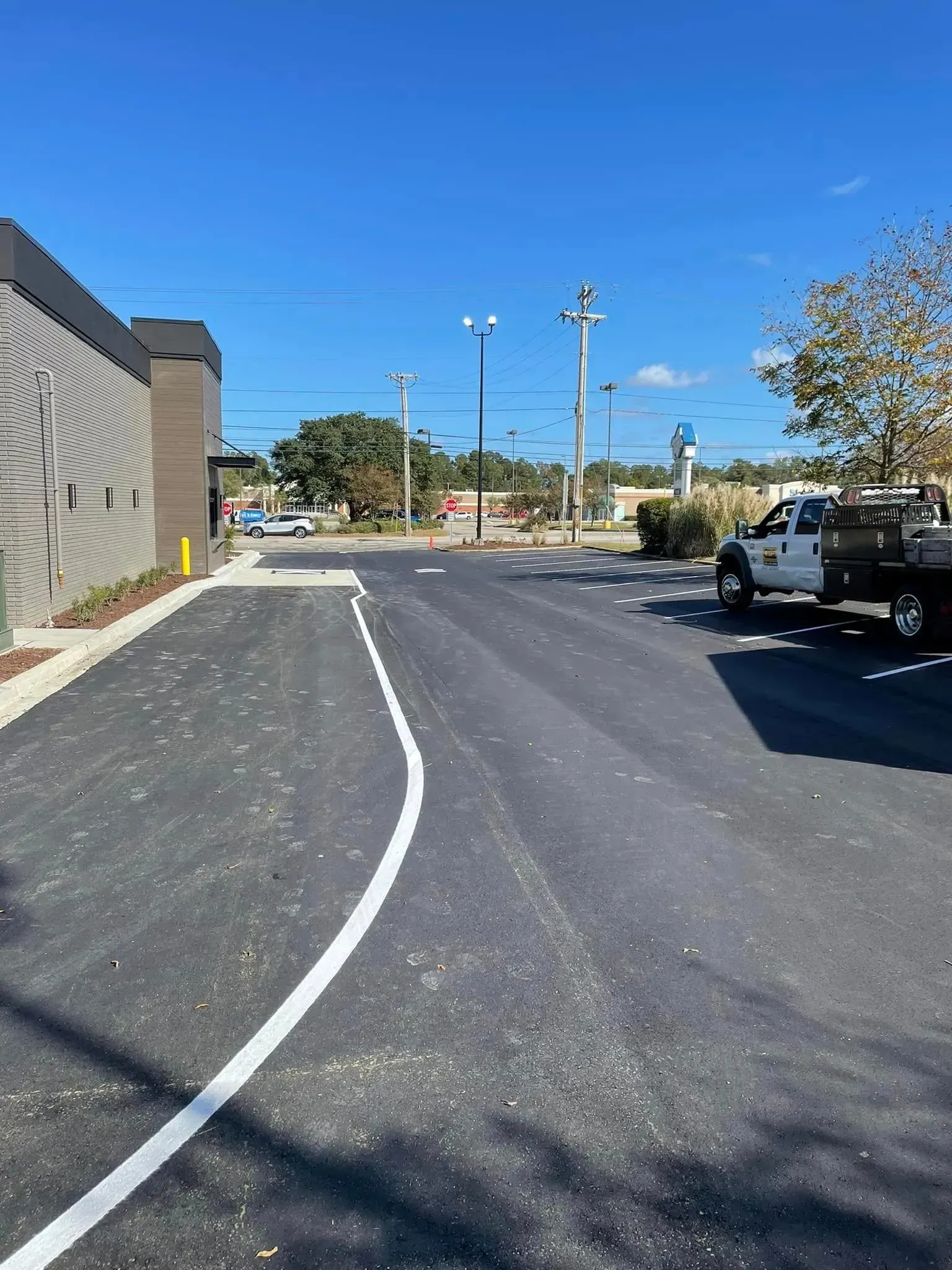 Empty parking lot with fresh white lane markings beside a building under a clear blue sky