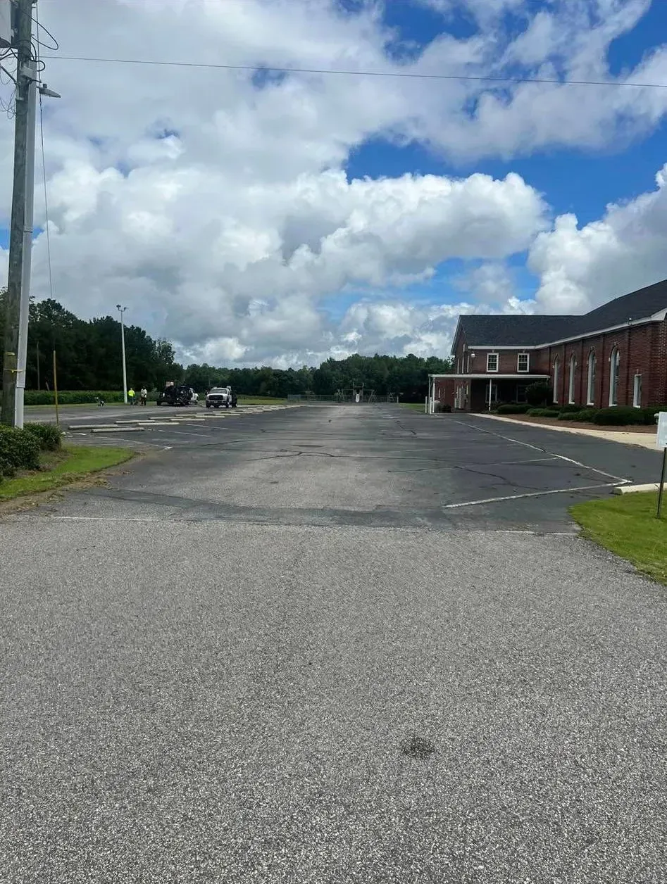 Empty parking lot beside a red brick building under a partly cloudy sky