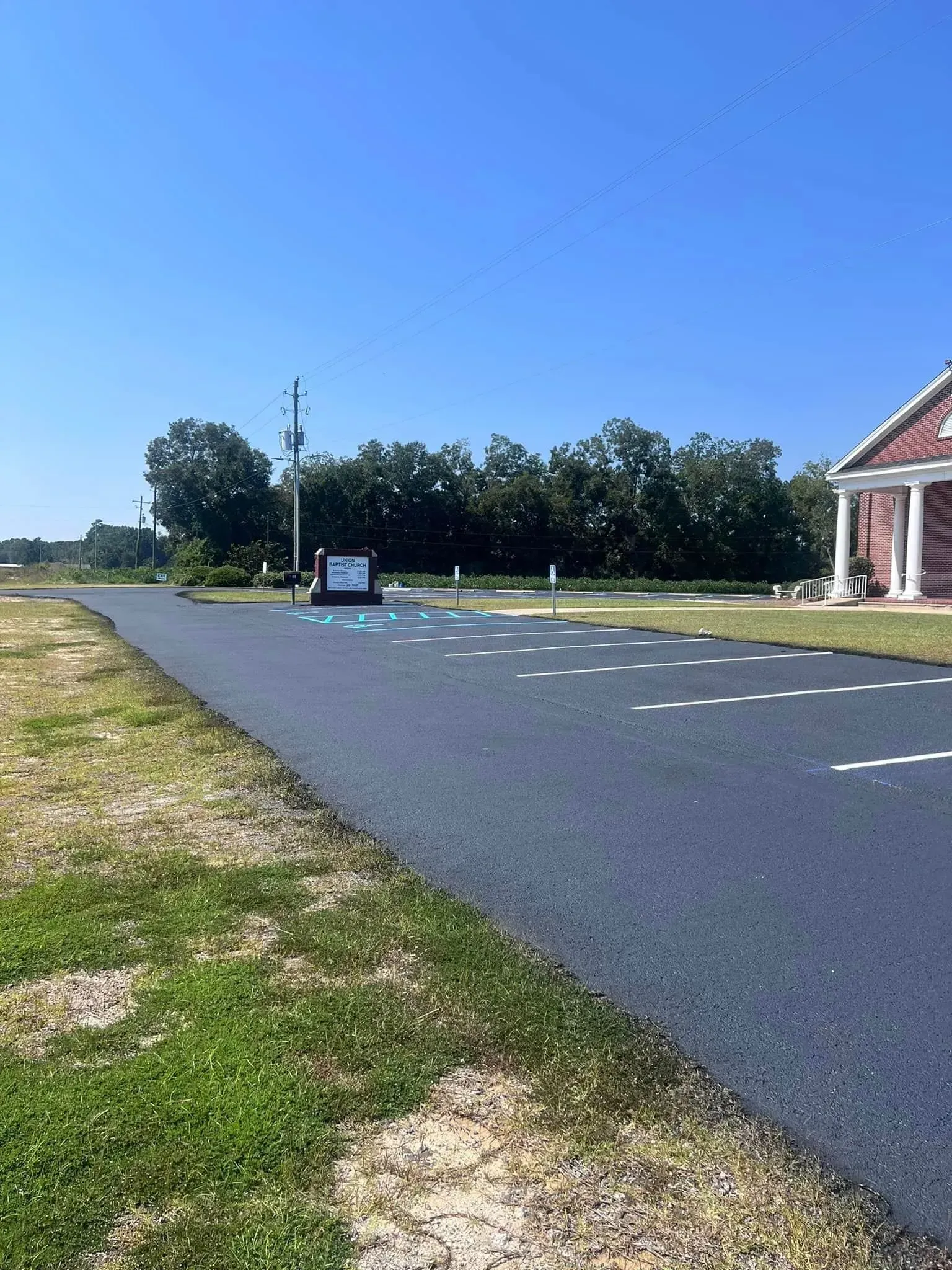 Empty paved lot beside a red-roofed building under a clear blue sky