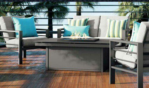 A patio with a couch , chairs , and a fire pit.