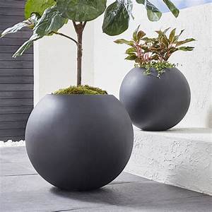 Two black planters with plants in them are sitting on a ledge.
