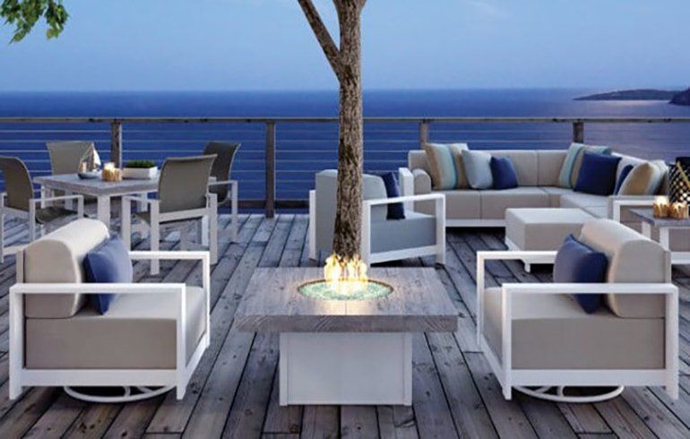 A wooden deck with furniture and a fire pit in the middle