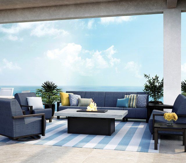 A patio with a couch and chairs and a fire pit