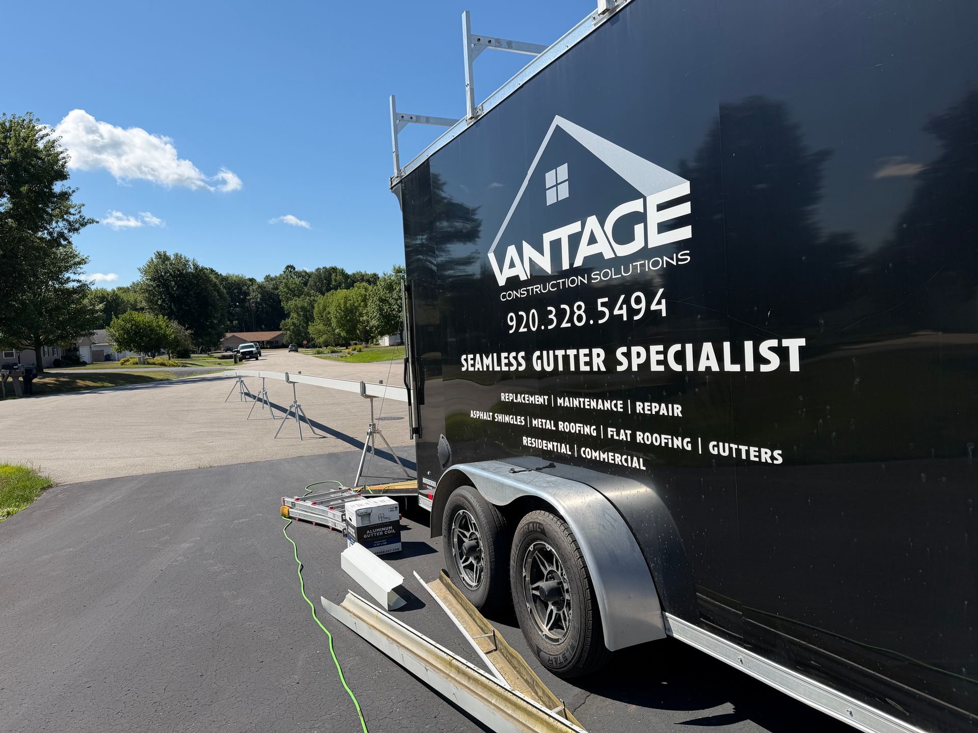 Black trailer with ANTAE logo parked roadside under a blue sky