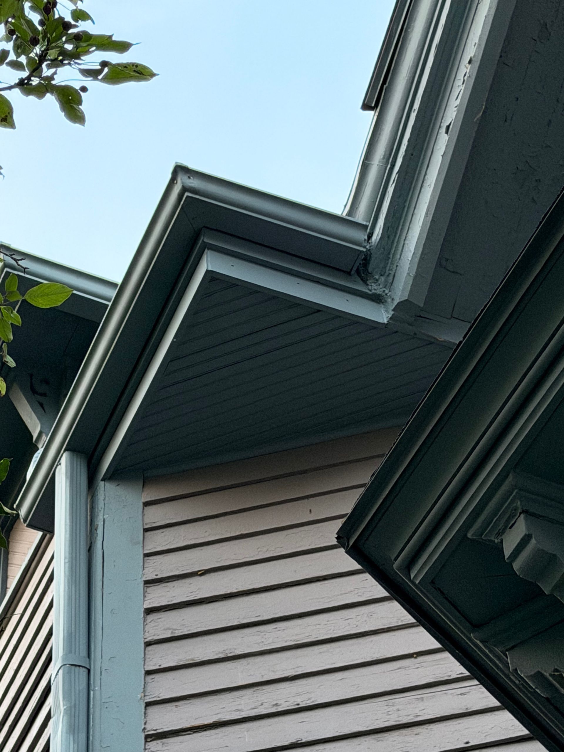 Close-up of a house exterior with gray siding, white trim, and dark roof eaves