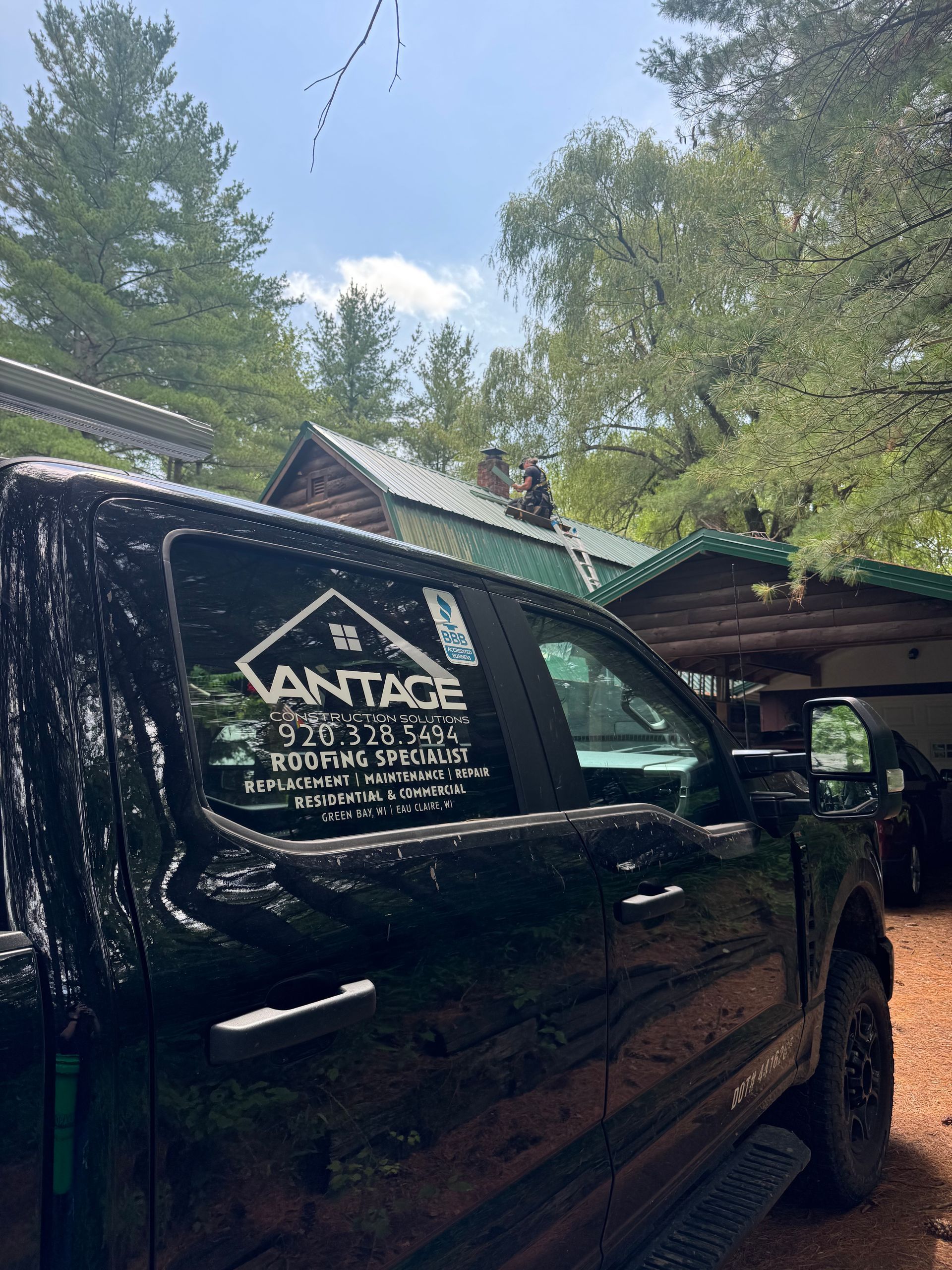 Black pickup truck with Vantage Cleaning Service logo parked under trees beside a house.