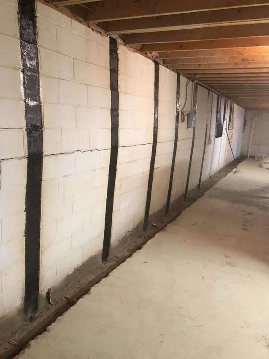 Unfinished basement wall with concrete block and wood framing along a narrow corridor