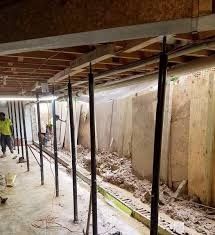 Interior view of a basement with support beams propping up a ceiling. A person is visible in the background.