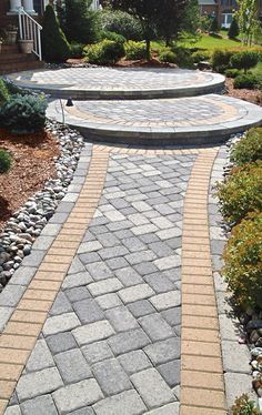 Stone paver pathway leading to tiered circular patios, surrounded by landscaping.