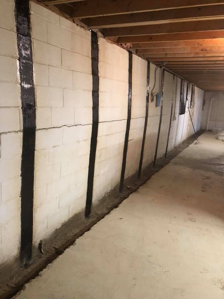 Basement wall with black carbon fiber strips for reinforcement; concrete floor.