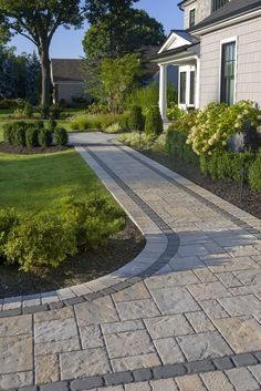 Stone walkway curving toward a house with manicured landscaping and shrubs.