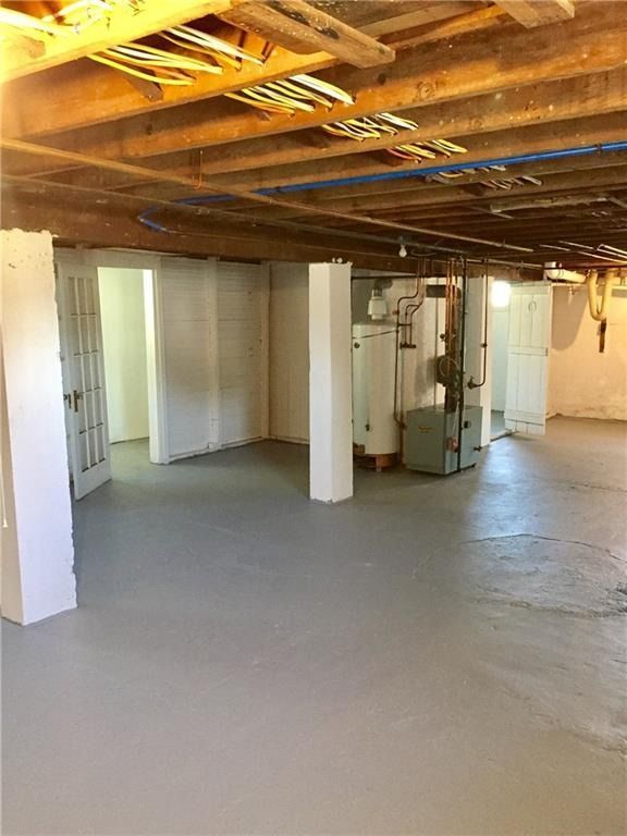 Basement with gray painted floor, white walls, support beams, and utility equipment.