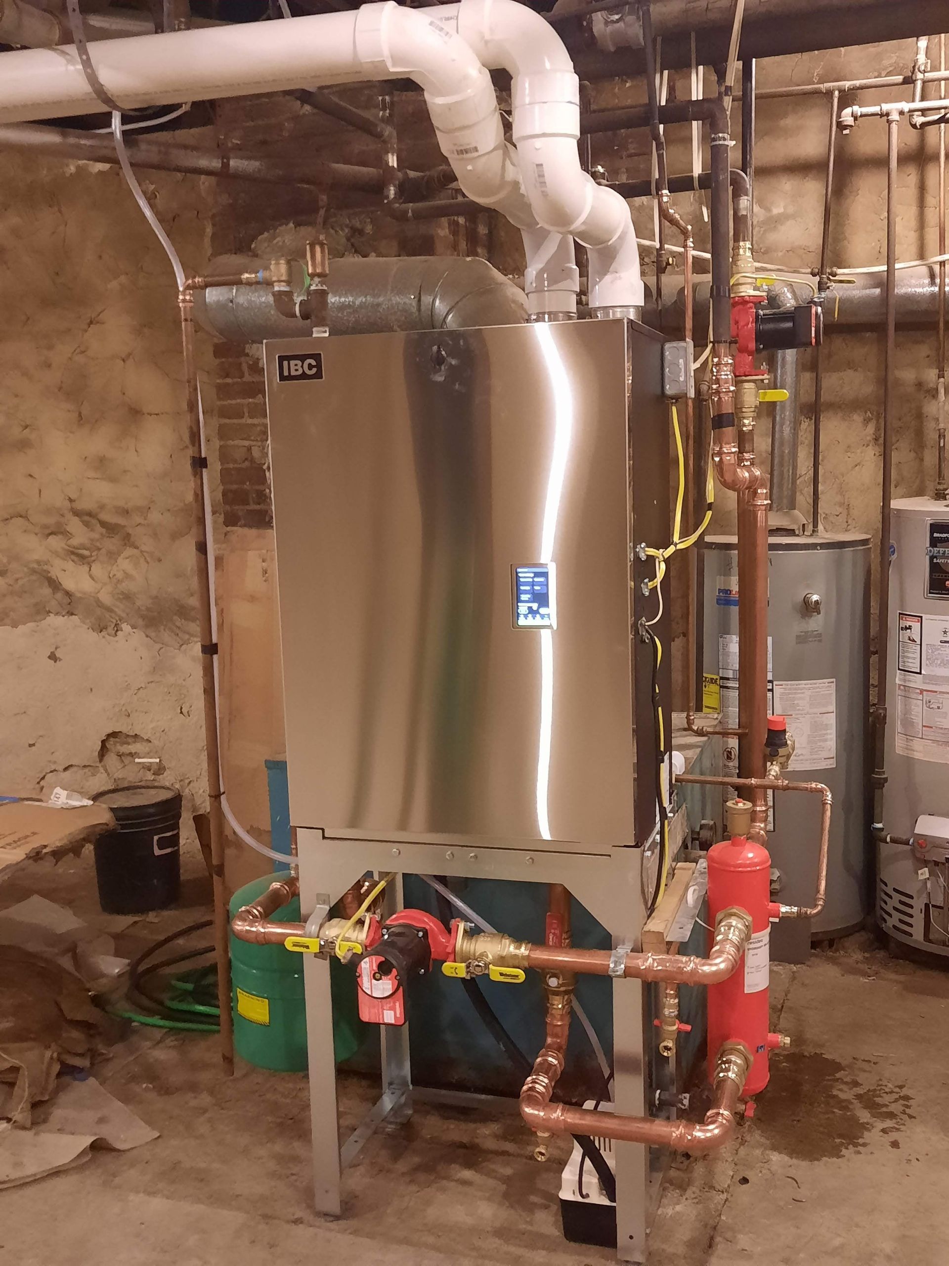 A stainless steel water heater in a basement.