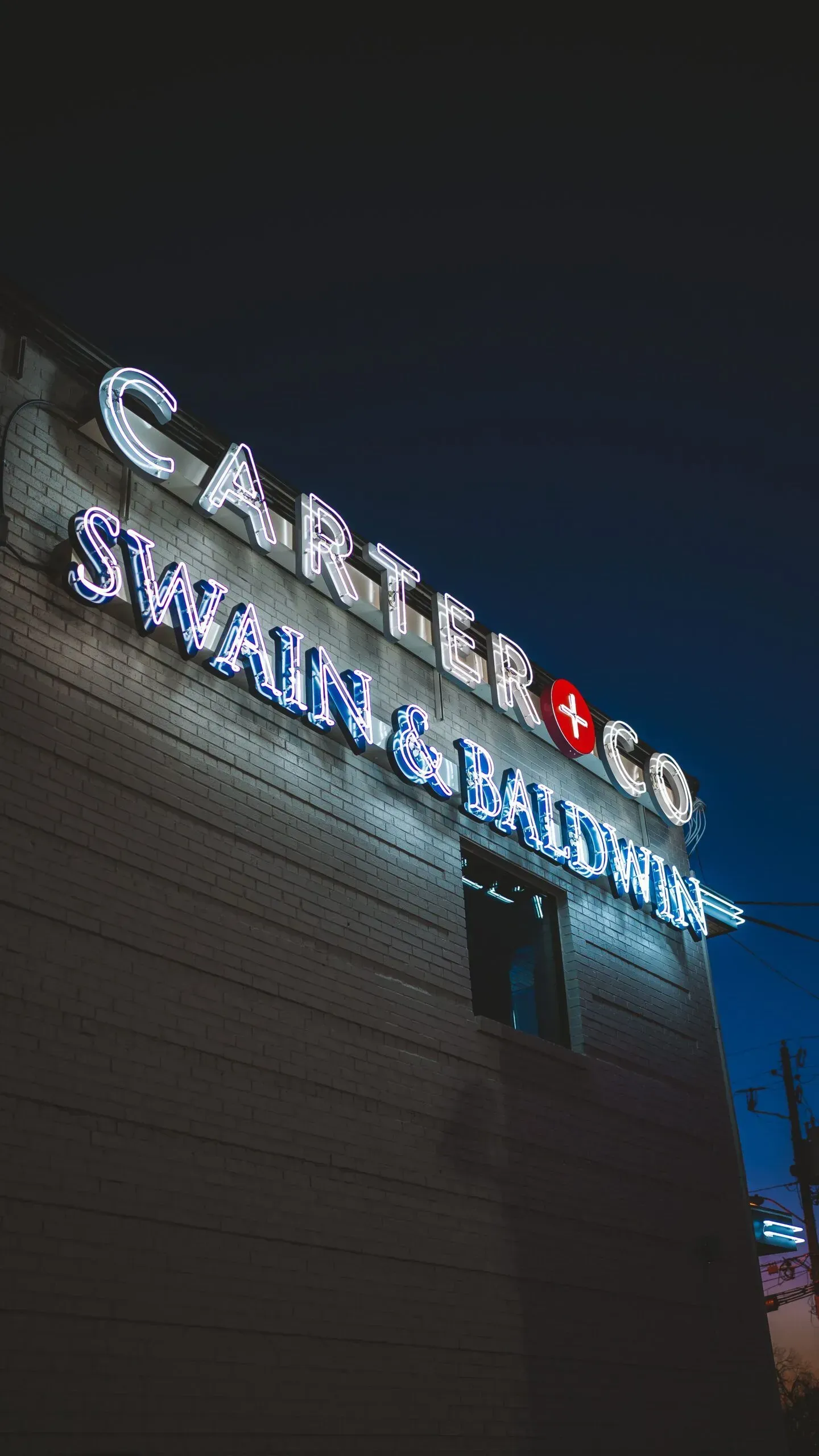 Neon sign of Carter & Co., Swain & Ballerstedt on a building at night.
