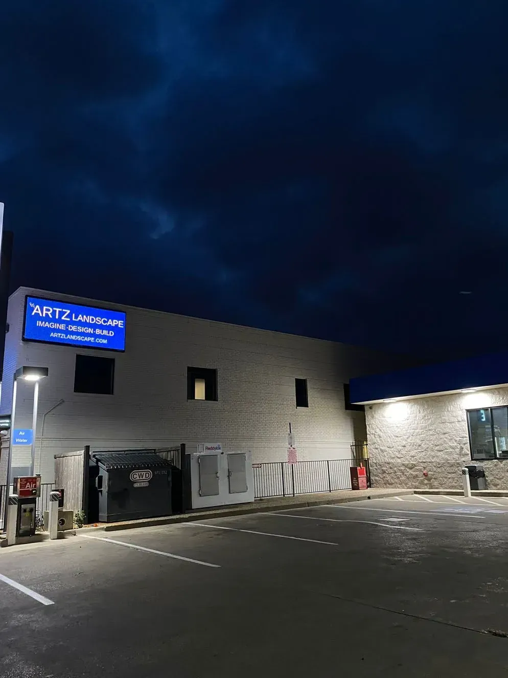 A gas station at night with a blue sign reading 