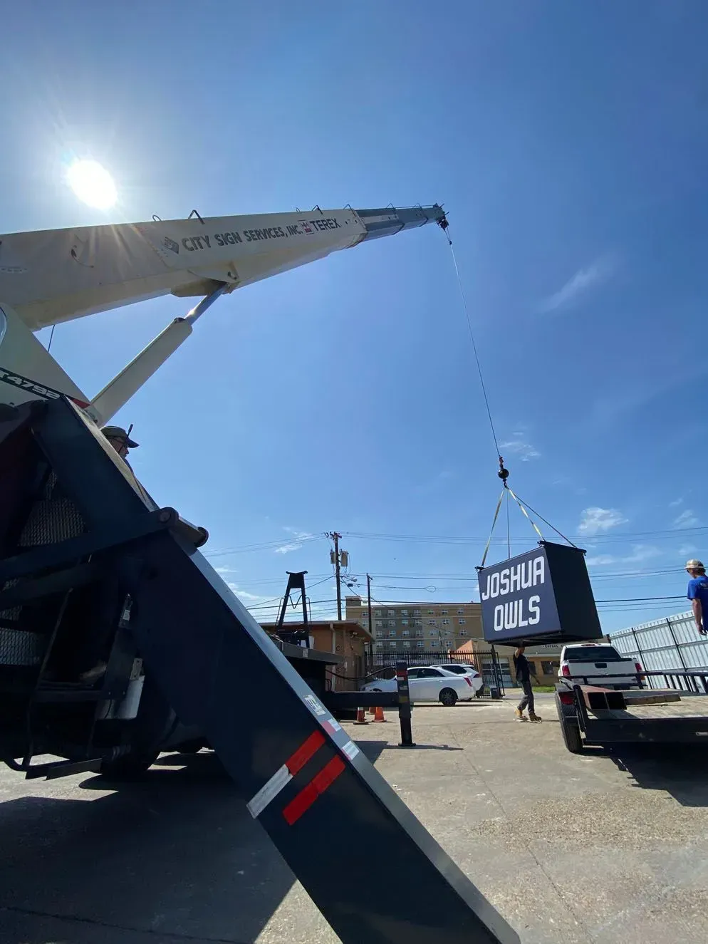 Crane lifting a rectangular sign that says 