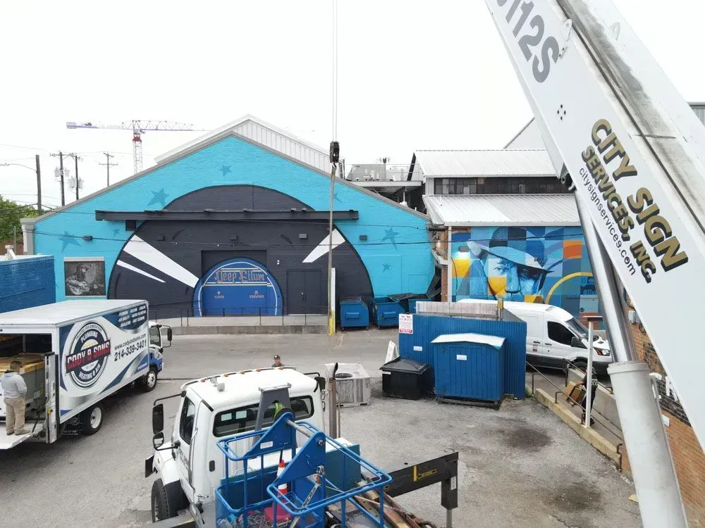 Construction site with crane, blue and white buildings, and trucks. 