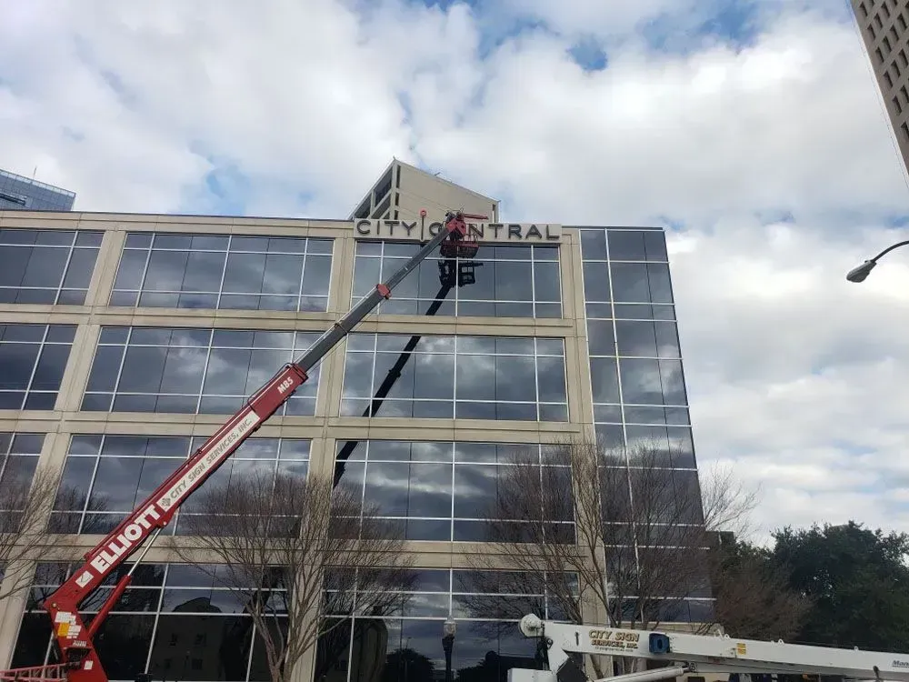 A cherry picker is installing signage that reads 