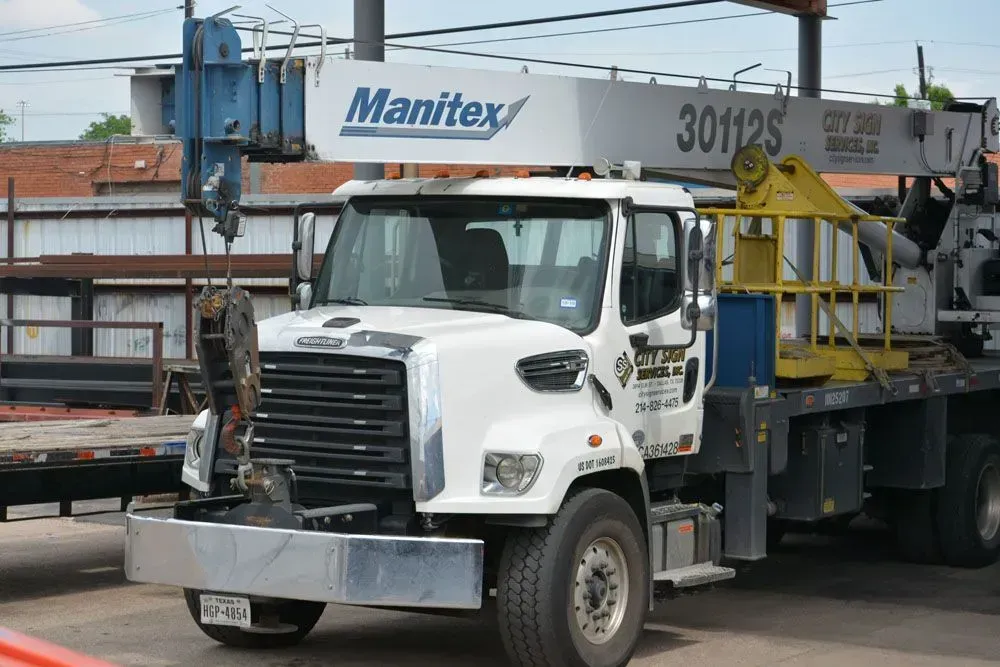White Manitex truck with crane boom extended, outdoors.