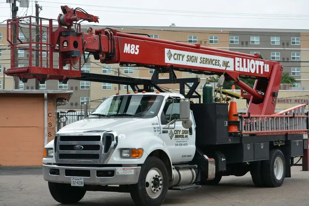 A white truck with a red Elliott aerial lift. The truck is labeled 