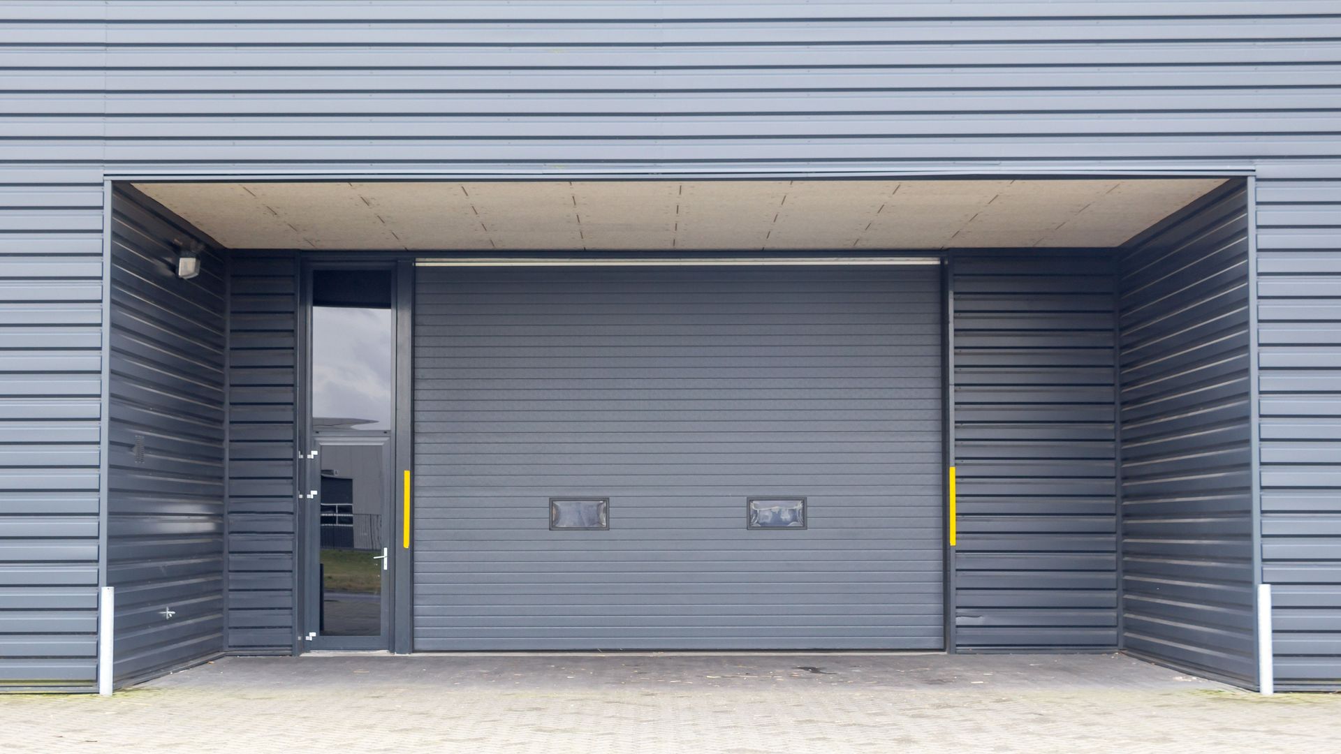 A large gray garage door with a glass door and a roof 