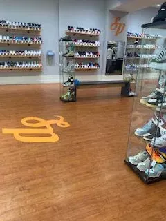 Empty shoe store with wall shelves of colorful shoes and a glass display case on the right.