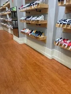 Shoe store aisle with shelves of colorful sneakers along a wood floor