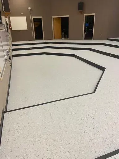 Empty lecture hall with stepped seating and gray carpeted floor.