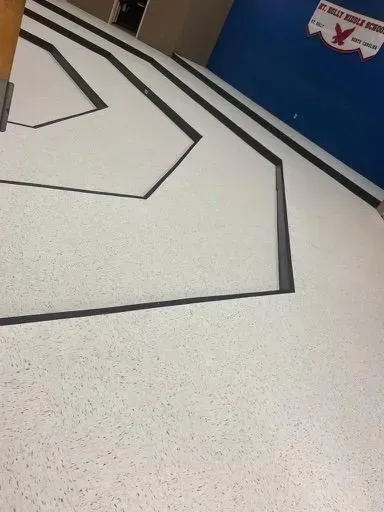 White floor with black geometric lines in a hallway beside a blue wall and doorway