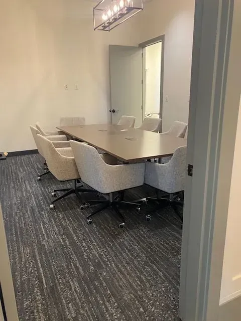Empty conference room with beige chairs around a long table and a closed door in the background