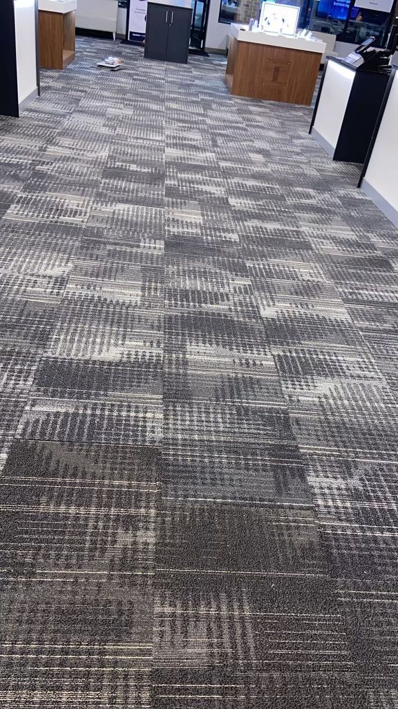 Office hallway with gray patterned carpet and desks along the sides
